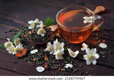 red butterfly on jasmine flowers. green tea with jasmine on the table. green tea leaves, jasmine flowers and cup of tea close-up