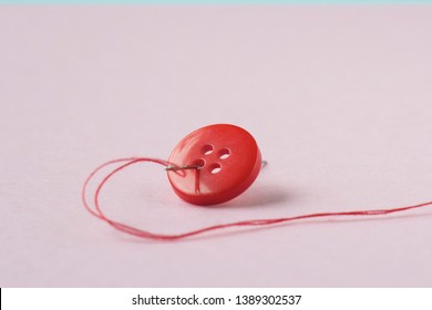 Red button, red thread and needle close up.