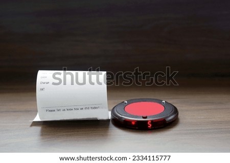 A red button for warning  get received food on a wooden floor with a bill in the background in the restaurant.