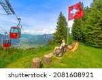 Red cable car cabin from Chur to Kanzeli and Brambruesch in Switzerland. Woman relaxing on top of Brambruesch. Swiss cable car of Chur or Coira with Swiss flag in Grisons canton.