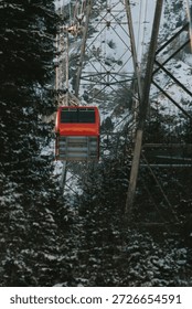 Red cable car moving up through a snow covered forest in the mountains