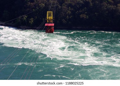 Red Cable Car Over Green And White Whirl Pool Water 