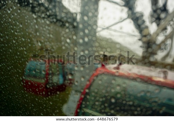 Red cable car in rainy day with drop of water on\
the window in blur scence