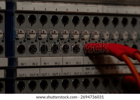 Red Cable Connected to Audio Interface Panel with Multiple Input and Output Ports