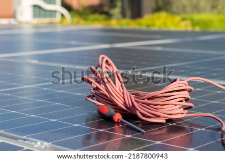Red cable reel and a screwer prepared to get the photovoltaic solar installation ready and get free energy