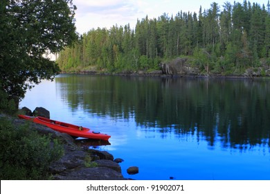 Red Canoe Sitting On The Rocks At The Lake In Minnesota, USA