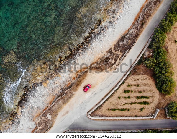 Red car from above near\
ocean