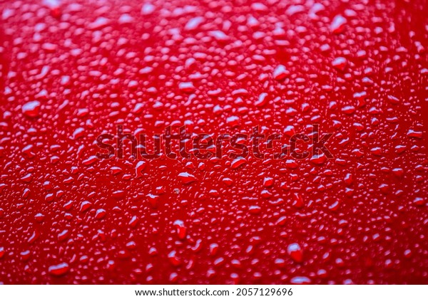 Red car after rain. Water drops collect on top of\
metal surfaceWater drops