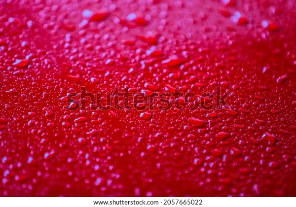 Red car after rain. Water drops collect on top of
metal surfaceWater drops
