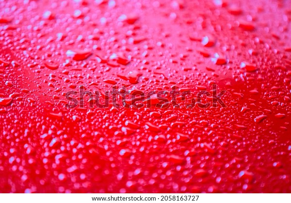 Red car after rain. Water drops collect on top of\
metal surfaceWater drops