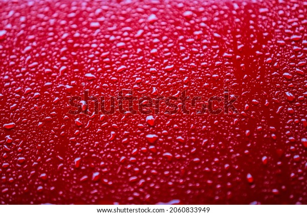Red car after rain. Water drops collect on top of
metal surfaceWater drops