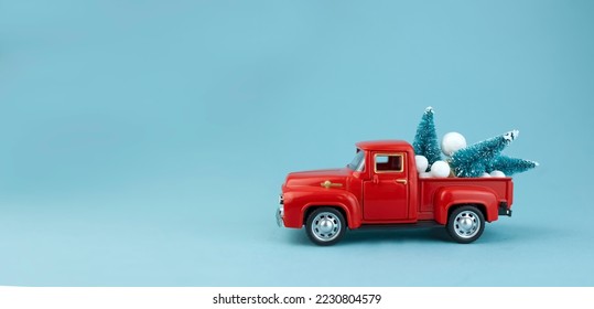 The red car is carrying green Christmas trees in the back. Christmas card with copy space on a blue background. High quality photo - Powered by Shutterstock