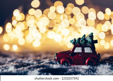 Red Car With A Christmas Tree Driving Through Snowy Road. Fairy Lights, Wintertime.