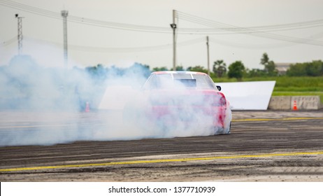 Red Car drifting, Car wheel spinning with smoke coming from wheels, Drag Racing on asphalt track.