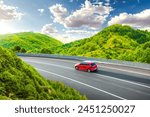 Red car driving on nature road between green mountains in summer. Nature landscape on highway for summer vacation travel. Mountain road view on beautiful nature trip in Europe. car drive on highway.