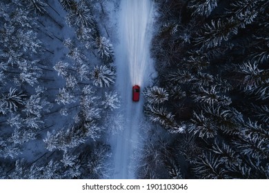 Red Car Driving On Winter Mountain Road At Night Time. Beautiful Aerial View With The Trees Covered In Snow. Light In The Dark.