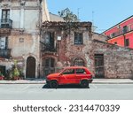 Red car in front of dilapidated building in Abruzzo, Italy