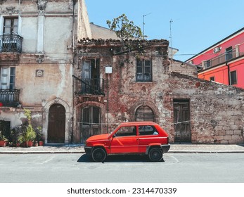 Red car in front of dilapidated building in Abruzzo, Italy
