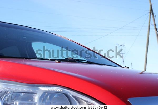 red car front view. Elements of car bright red\
against the sky on a winter sunny day. Photo of car part,\
Background image, Car front\
end.