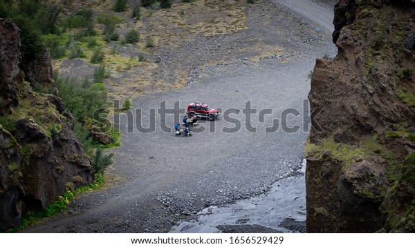 Red car with group of tourist parked in the canyon.\
Iceland 