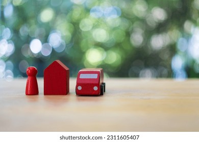 Red car, home and human figure model on the table against nature background - Shutterstock ID 2311605407
