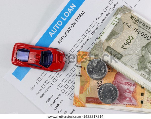 Red car with indian currency notes,\
coins and application paper. Car loan. Auto\
finance.