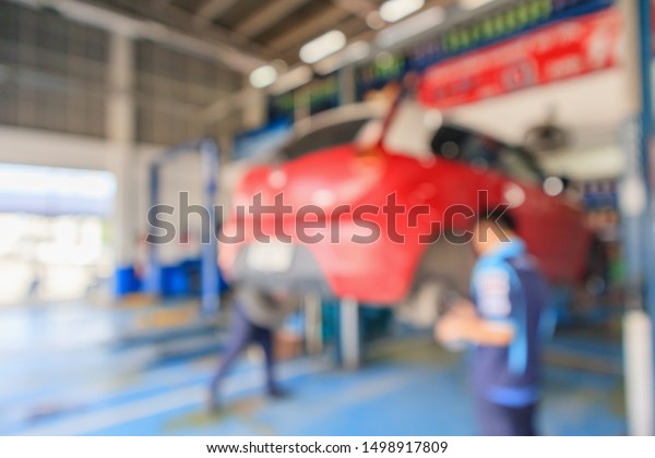 Red car lift at maintenance station\
in automotive service center blur abstract\
background
