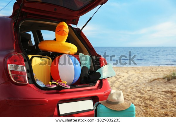 Red car\
with luggage on beach. Summer vacation\
trip