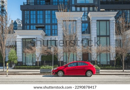Red car on the empty urban street in a sunny day. Car parked in downtown of Vancouver Canada. Modern architecture view with car parked on a street. Nobody, street photo