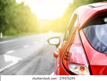 Red Car On The Road At Sunset.