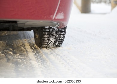 A Red Car Is Parked In The Side Of The Road On A Winter Day. Snow Is On The Ground.