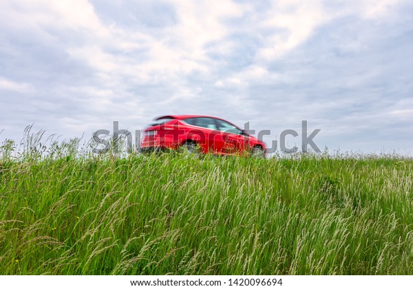 Red car passing by in motion blur at the\
swedish countryside.
