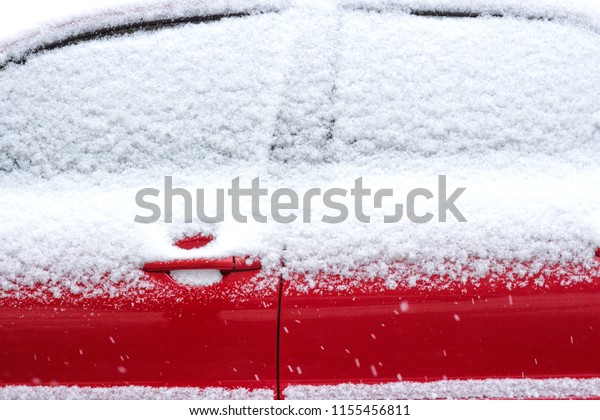 Red car in the snow. The windows of the car are\
covered with snow