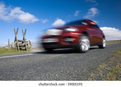 Red Car Speeding On Empty Mountain Road. Dartmoor National Park, Devon, UK.