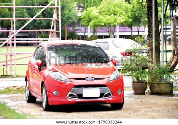 The red car of Thai teacher was\
parked outside and was washed by the rain in the mean\
time.