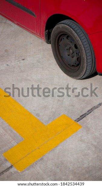 Red car tyre on grey ground and yellow line in parking\
lot 