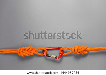 Red carbine with clutch. Equipment for climbing and mountaineering. Safety rope. Knot eight.