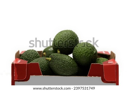 Red cardboard box full of bright green avocados on a white background, healthy food