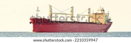 Red cargo ship (bulk carrier) sailing in the Baltic sea. Freight transportation, nautical vessel, logistics, industry, commerce, economy, environmental damage. Panoramic view, seascape