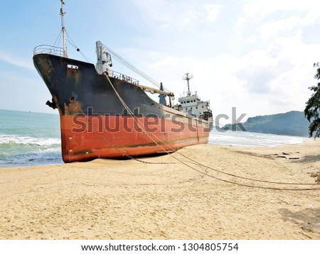 Red cargo ship stranded on a beach attached with ropes in Vietnam
