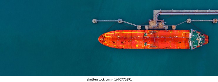Red cargo tanker ship vessel at port with marine loading arms platform, Global business oversea commercial trade logistic import export oil and gas petrochemical from refinery industry transportation.