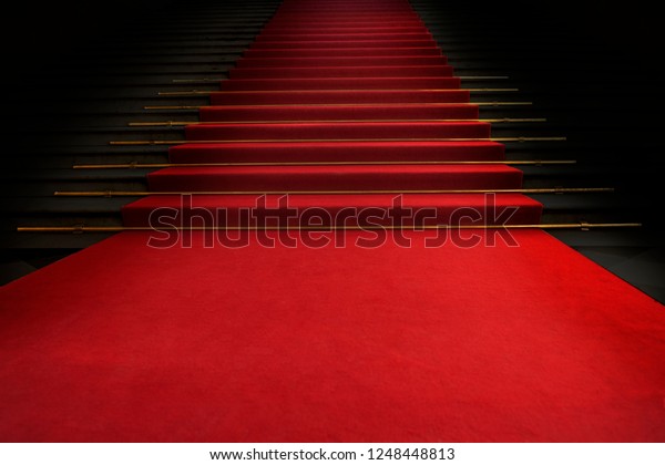 Red carpet on the stairs on a dark\
background. The path to glory, victory and\
success