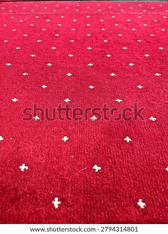 Red carpet texture with small white geometric dot pattern, luxury fabric background, abstract textile surface, perspective view and repeating decorative design.