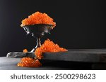 Red caviar in bowl on black background. Salmon roe. Delicacy. Delicious dish. Texture of caviar. Seafood. Copy space.