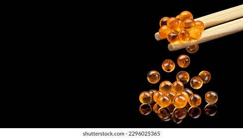 Red caviar on chopsticks for sushi isolated on black background