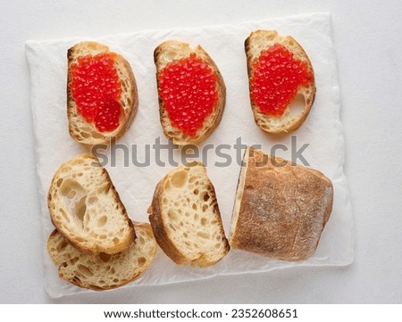 Red caviar on slices of white wheat bread on a white table, concept of luxury and gourmet cuisine, top view