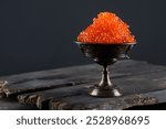 Red caviar. Salmon roe in vase on black background. Delicacy. An exquisite snack. Useful omega.