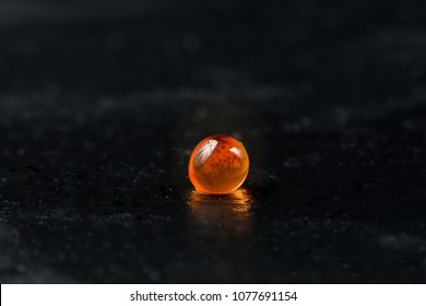 Red Caviar. Single Fish Egg On Dark Stone Background.