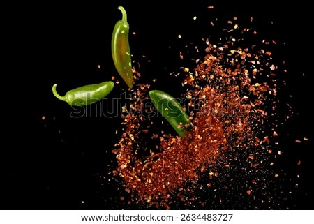 Red cayenne pepper explosion with three flying small green chilli peppers on black background