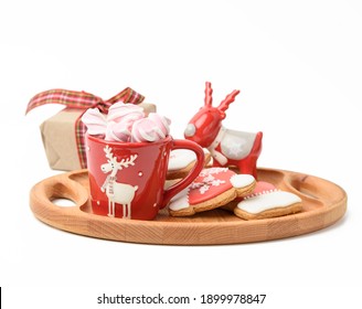 red ceramic cup with drink and marshmallows, near baked christmas gingerbread, white background